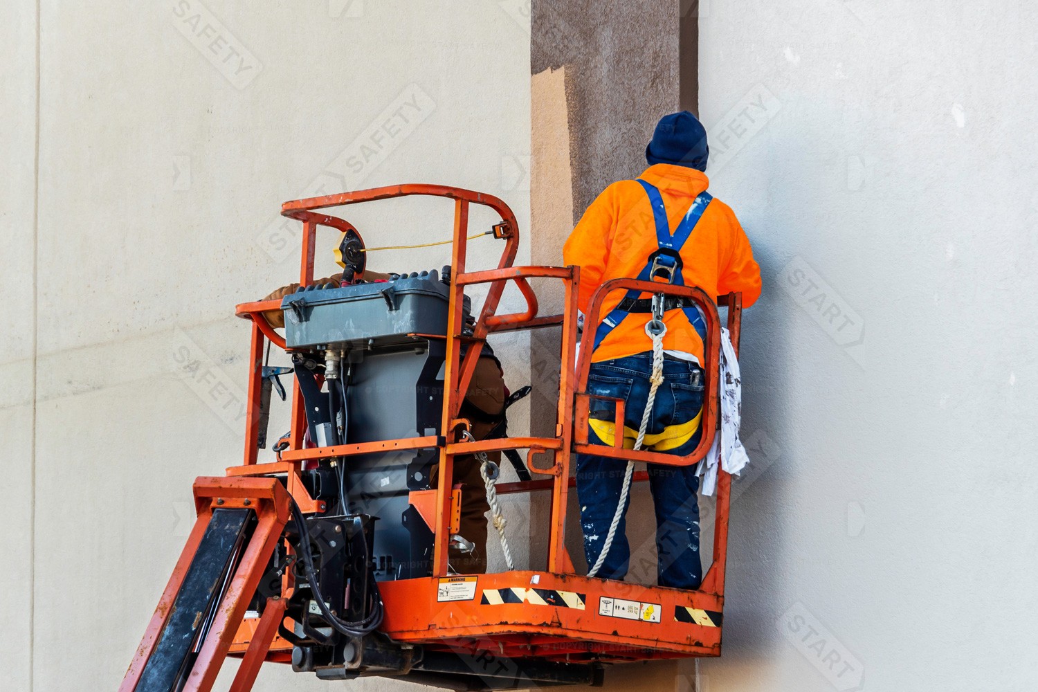 A Worker Wearing A Harness And Fall Restraint Lanyard In A Cherry Picker